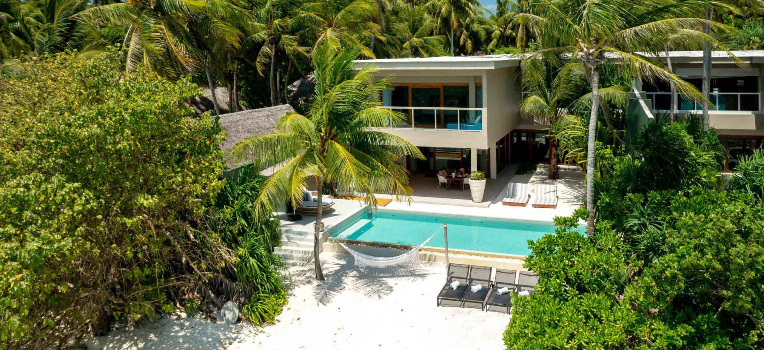 An exterior view of the freshwater pool and beach hammock at our private beachfront Family Residences and Villas.