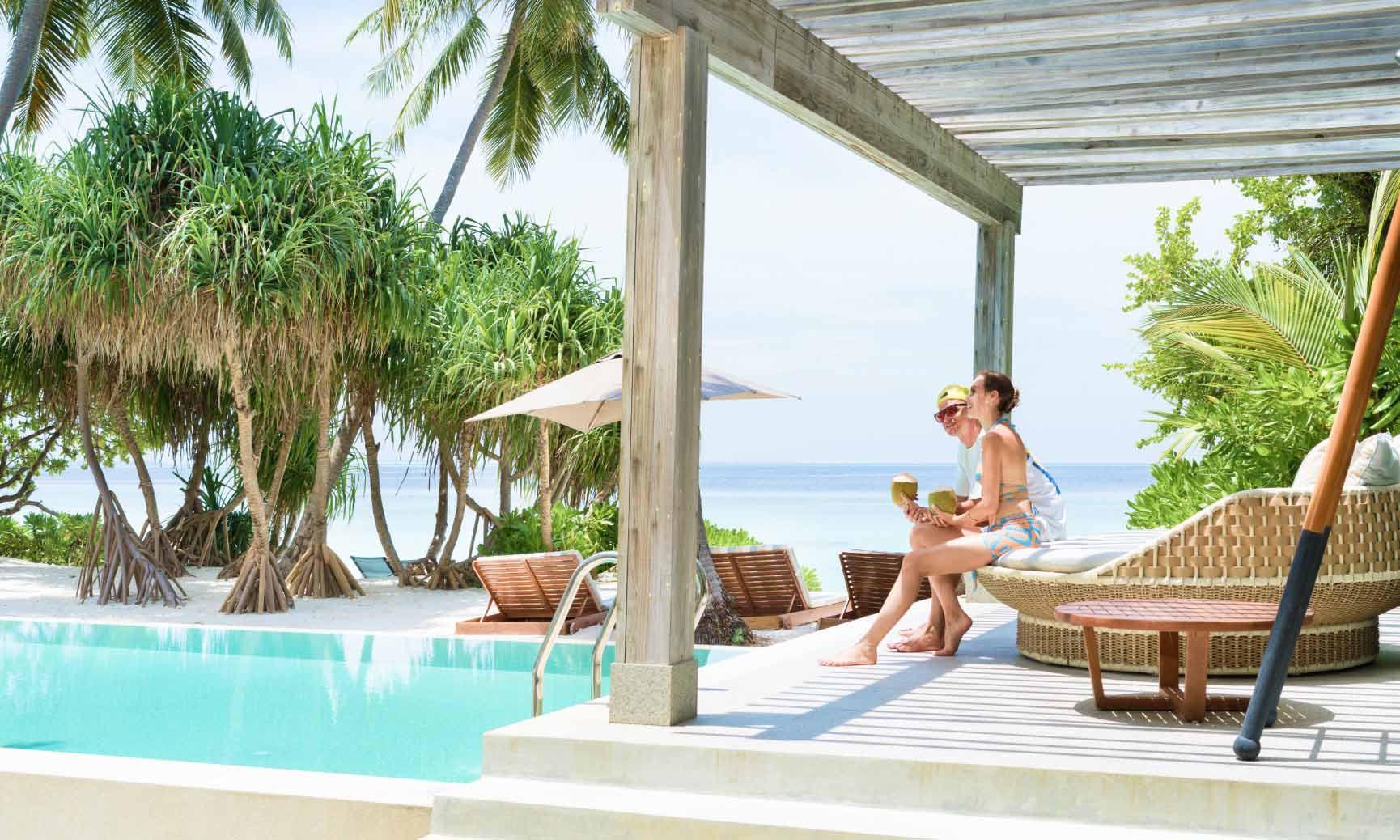 A couple relaxing on one of the outdoor day bed next to the private freshwater pool at the Great Beach Residence Maldives.