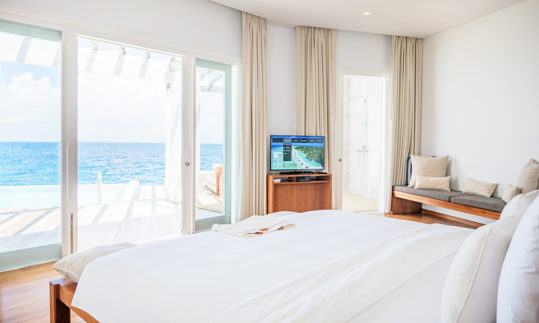 A bedroom with 1 king bed inside of our 2 bedroom water villa in the Maldives.